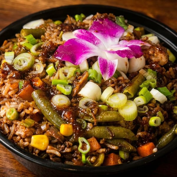 Close-up of a dark bowl filled with fried rice, vegetables, and chicken, garnished with a purple orchid.